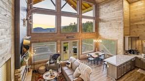 A spacious cabin with a large dining area, kitchen, and a cozy living room with a fireplace. - Three Pines 2 Bedroom Home (Sevierville)