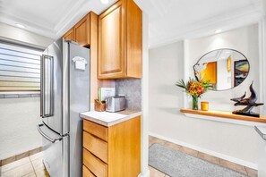Een moderne keuken met houten kastjes, een roestvrijstalen koelkast, een broodrooster en een decoratieve spiegel aan de muur.