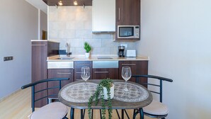 Una cocina moderna con una mesa de comedor, dos sillas, una planta en maceta y un microondas.