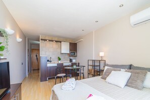 A compact hotel room with a bed, bedside table, and a kitchenette area. - 0114-MIAMI Studio with seaview (Empuriabrava)