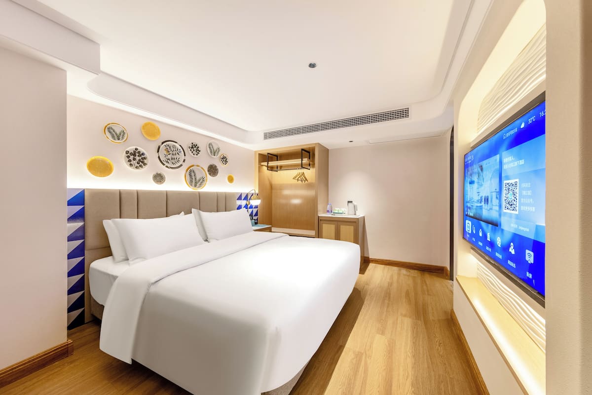 Una habitación de hotel moderna con una cama grande, un televisor de pared y un panel decorativo con varios diseños.