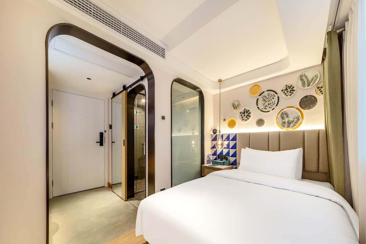 Habitación de hotel con una cama grande, un espejo, una mesita de noche y una pared con adornos de platos.