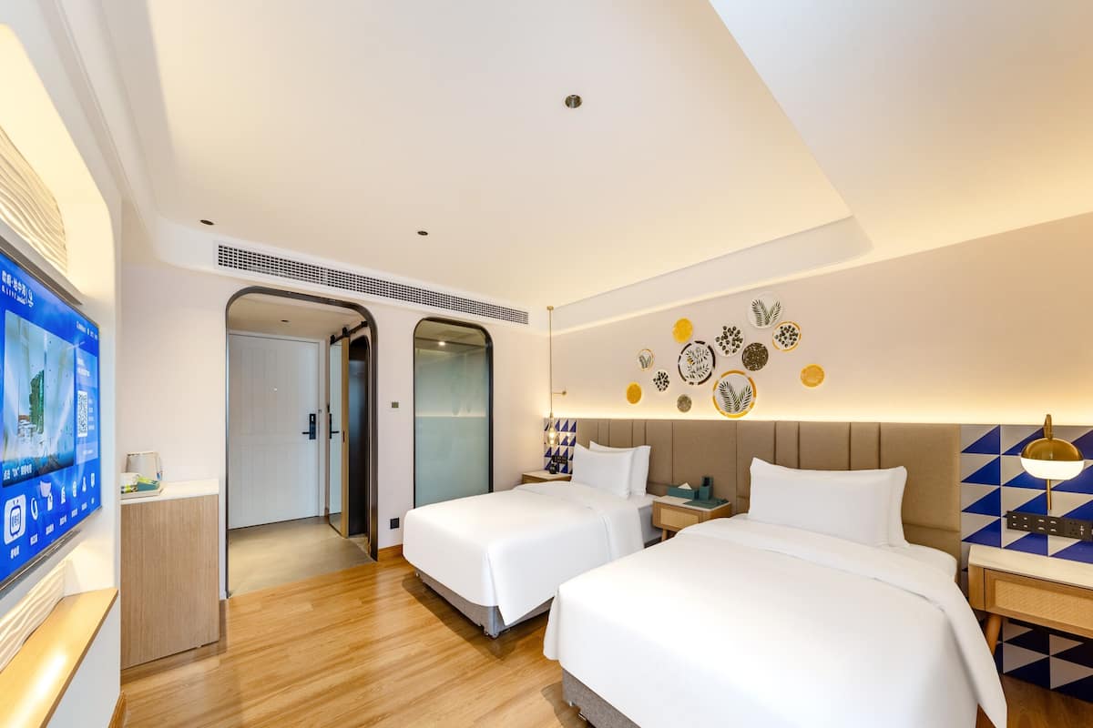 Habitación de hotel con dos camas, televisión y una pared decorada con platos.