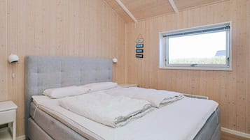 A bedroom with a bed, a bedside table, a window, and a wall-mounted sign.