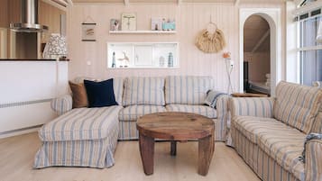 Una sala de estar acogedora con un sofá a rayas, una mesa de centro de madera y una pared decorativa con adornos.