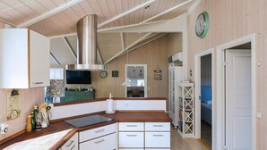 Una cocina con armarios de madera, una campana extractora de acero inoxidable, un horno empotrado y un reloj en la pared.