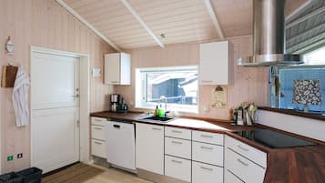 Una cocina moderna con armarios de madera, una campana extractora de acero inoxidable y un ventanal que proporciona luz natural.