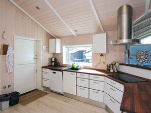 A modern kitchen with wooden cabinets, a stainless steel range hood, and a window providing natural light.