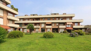A multi-story residential building with balconies, a central courtyard, and surrounding greenery. - Dolce Vita Baveno (Baveno)