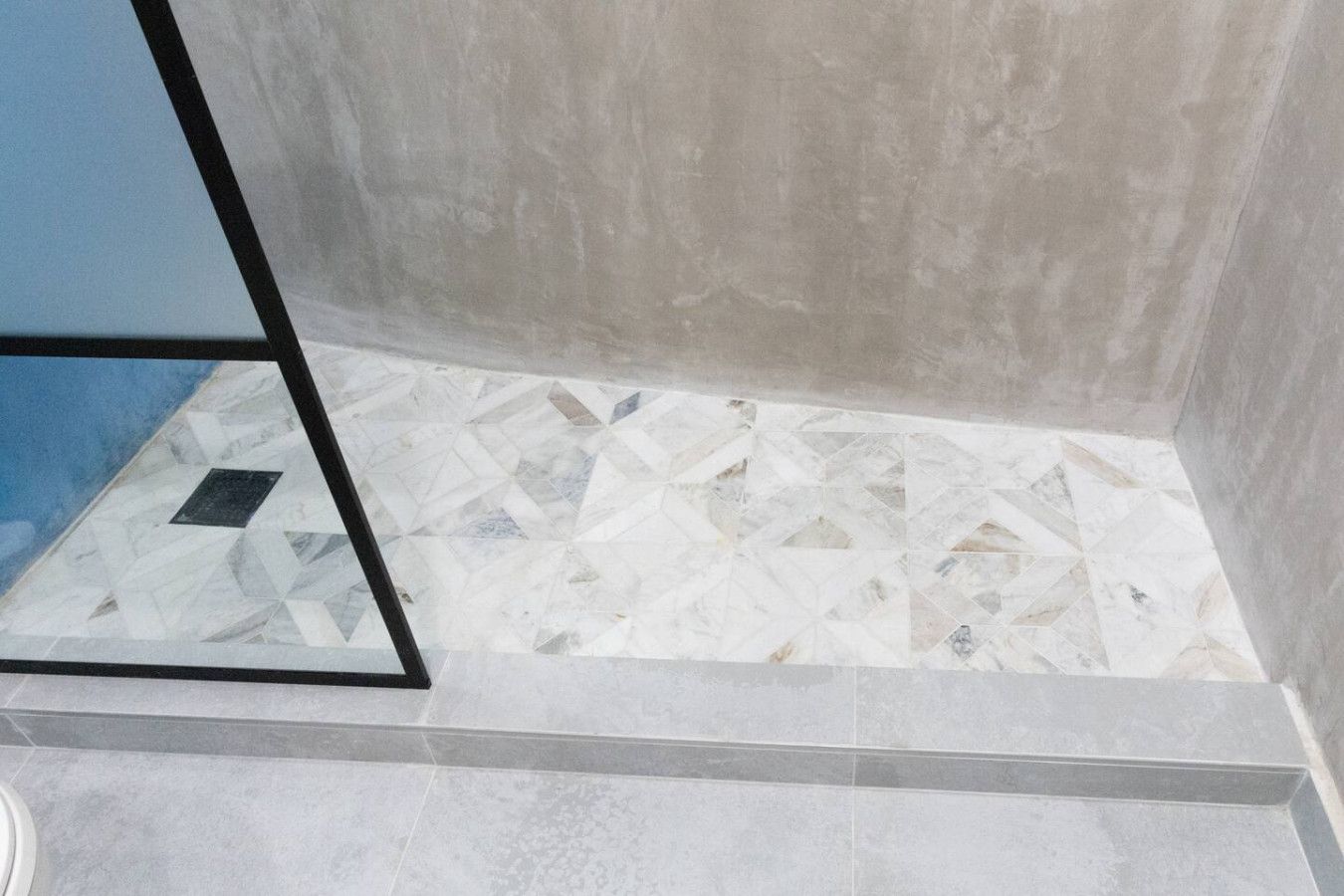 A bathroom with a geometric patterned tile floor, a black frame, and a blue wall.