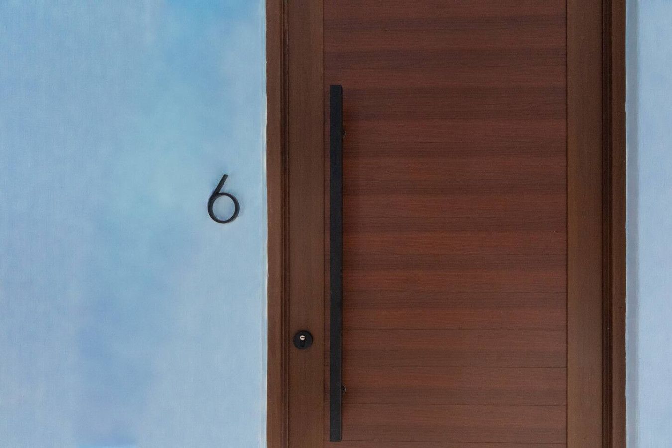 A wooden door with a handle and a number '6' on the wall to the left.