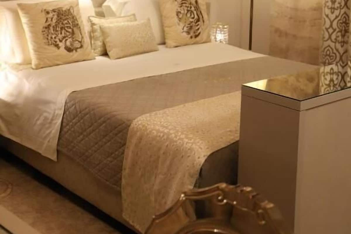 A hotel room with a large bed, a nightstand, a lamp, and a decorative wall.