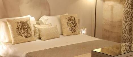 A hotel room with a large bed, a nightstand, a lamp, and a decorative wall.