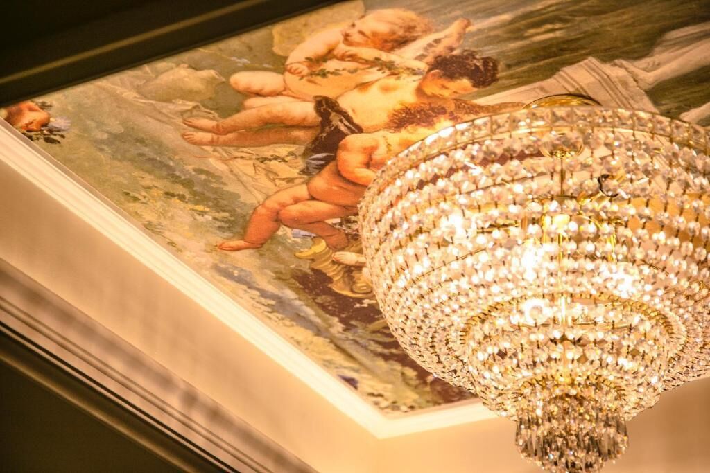 Un lustre à plusieurs niveaux, orné de cristaux, et une fresque au plafond représentant des anges.