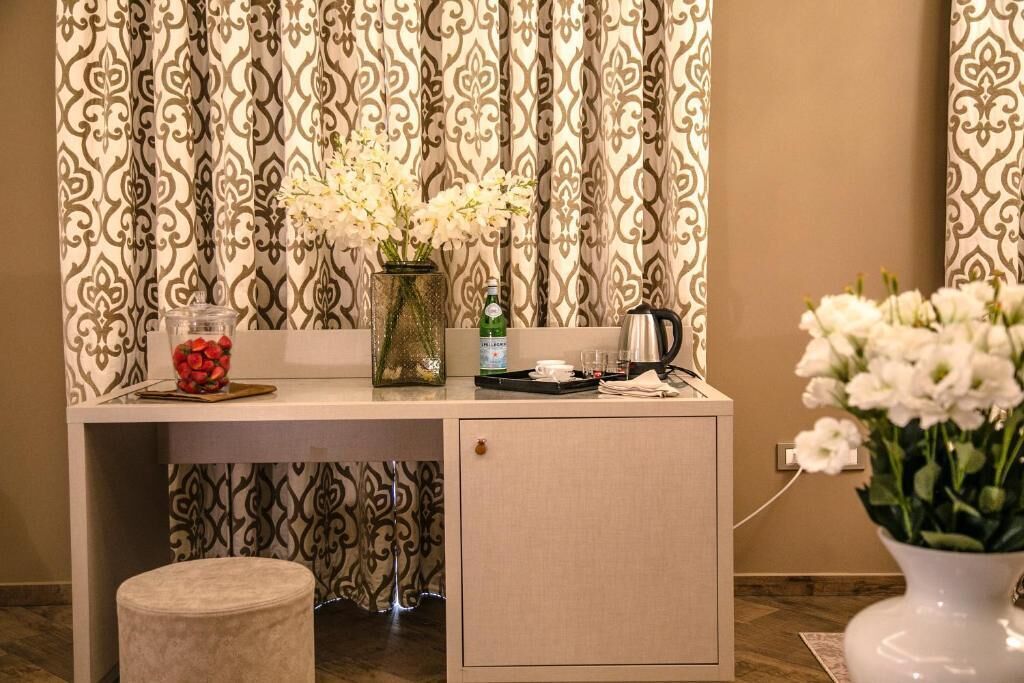 Un petit bureau bien rangé, agrémenté d’un vase de fleurs blanches, d’un bocal en verre, d’une bouteille et d’une bouilloire.
