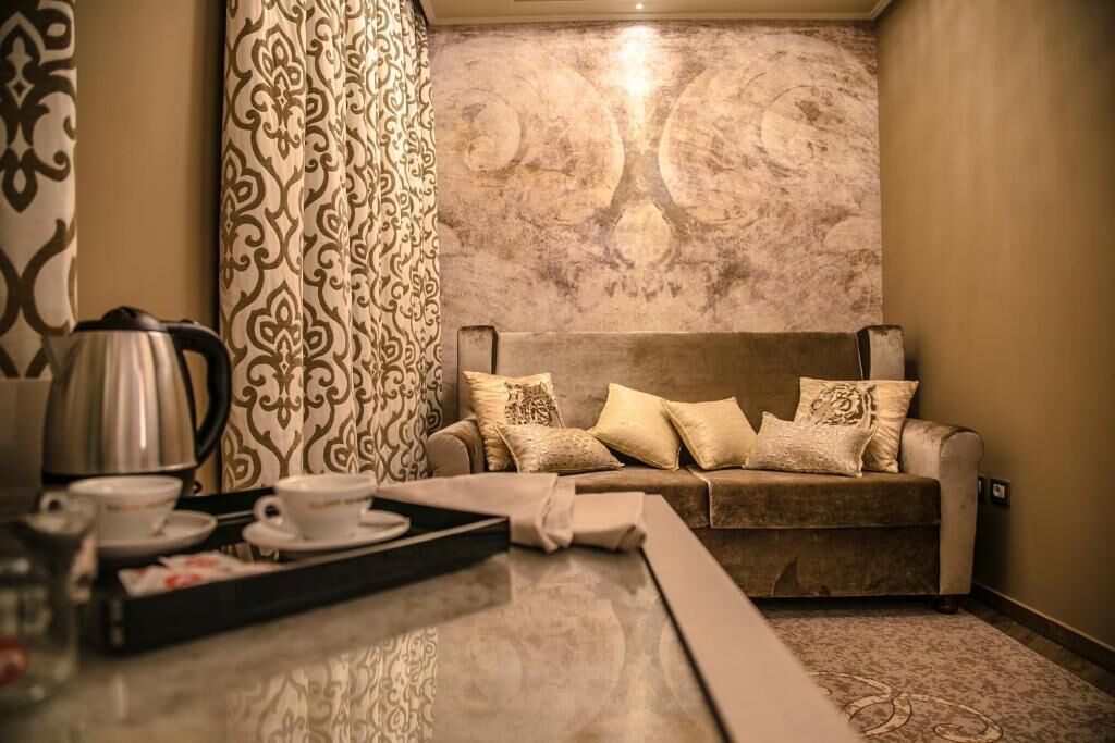 A cozy room with a sofa, patterned curtains, a coffee station, and a textured wall.