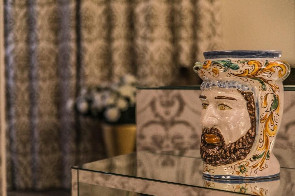 Una vitrina de vidrio con un jarrón de cerámica que presenta un diseño floral y un rostro.