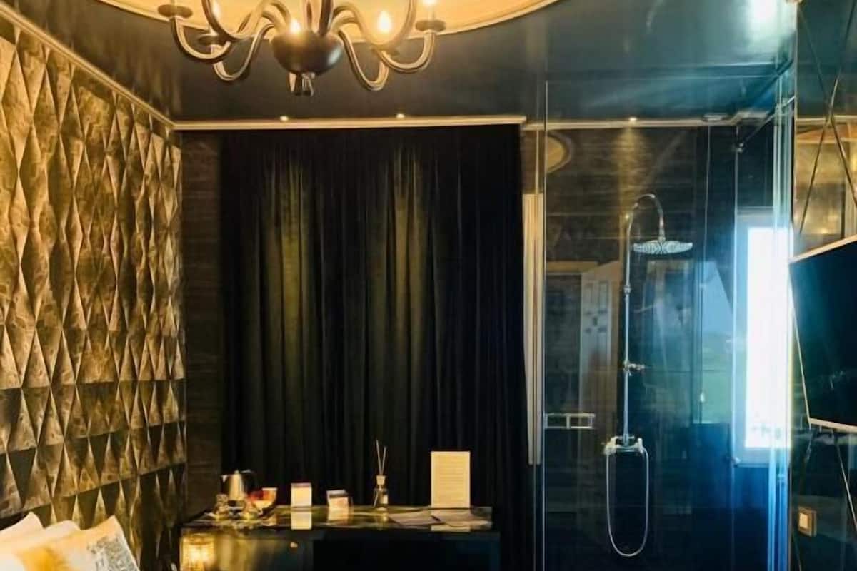 A modern bedroom with a large bed, a vanity with a mirror, and a walk-in shower.