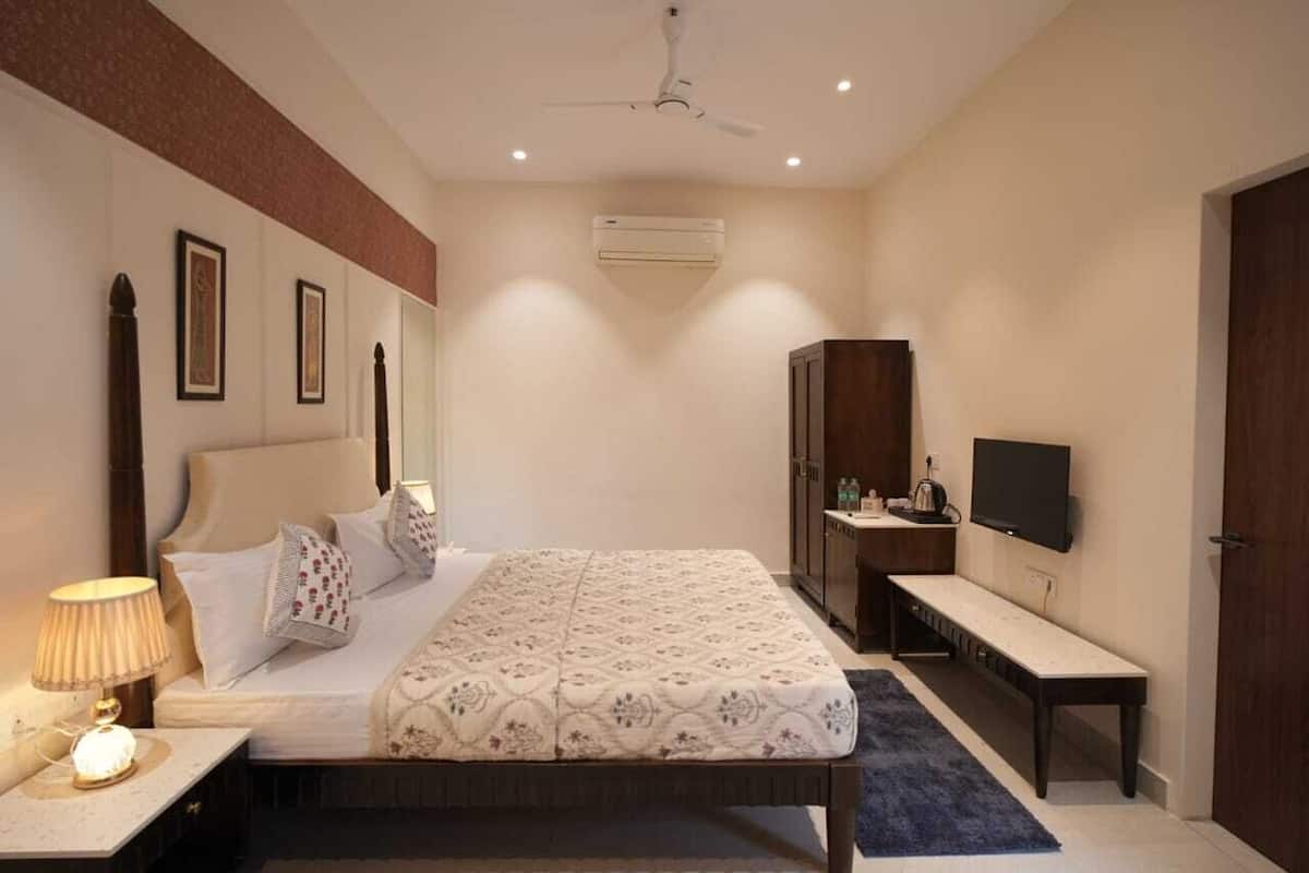 A bedroom with a bed, bedside table, lamp, wardrobe, TV, and a ceiling fan.