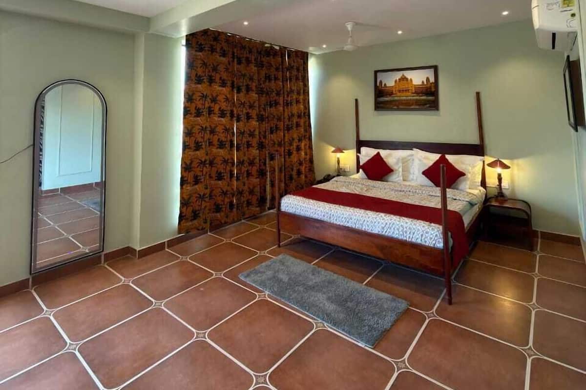 A bedroom with a bed, a nightstand, a wall-mounted air conditioner, and a door with a mirror.