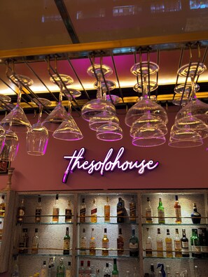 A bar area with a neon sign reading "thesohouse" and various bottles of liquor on shelves. - THE SOLO HOUSE (Jodhpur)