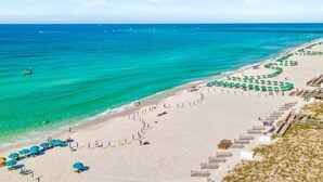 A beach with clear turquoise waters, a sandy shore, and rows of umbrellas.