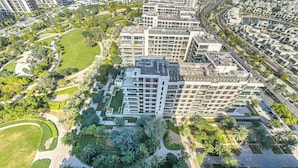 Un edificio residenziale a più piani con numerosi balconi, immerso nel verde e circondato da un parco curato.