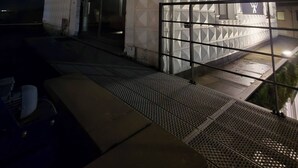 A small, white building with a gated entrance, a metal staircase, and a metal railing. - Modern Apartment in a Prime Location! (Tongeren)