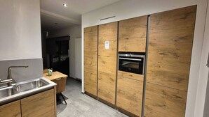 A modern kitchen with wooden cabinets, a stainless steel sink, and a built-in oven. - Modern Apartment in a Prime Location! (Tongeren)