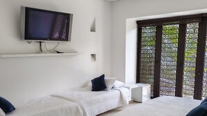 A hotel room with two beds, a TV mounted on the wall, and a ceiling fan.