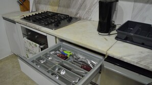 A kitchen with a gas stove, a coffee maker, and a drawer organizer.