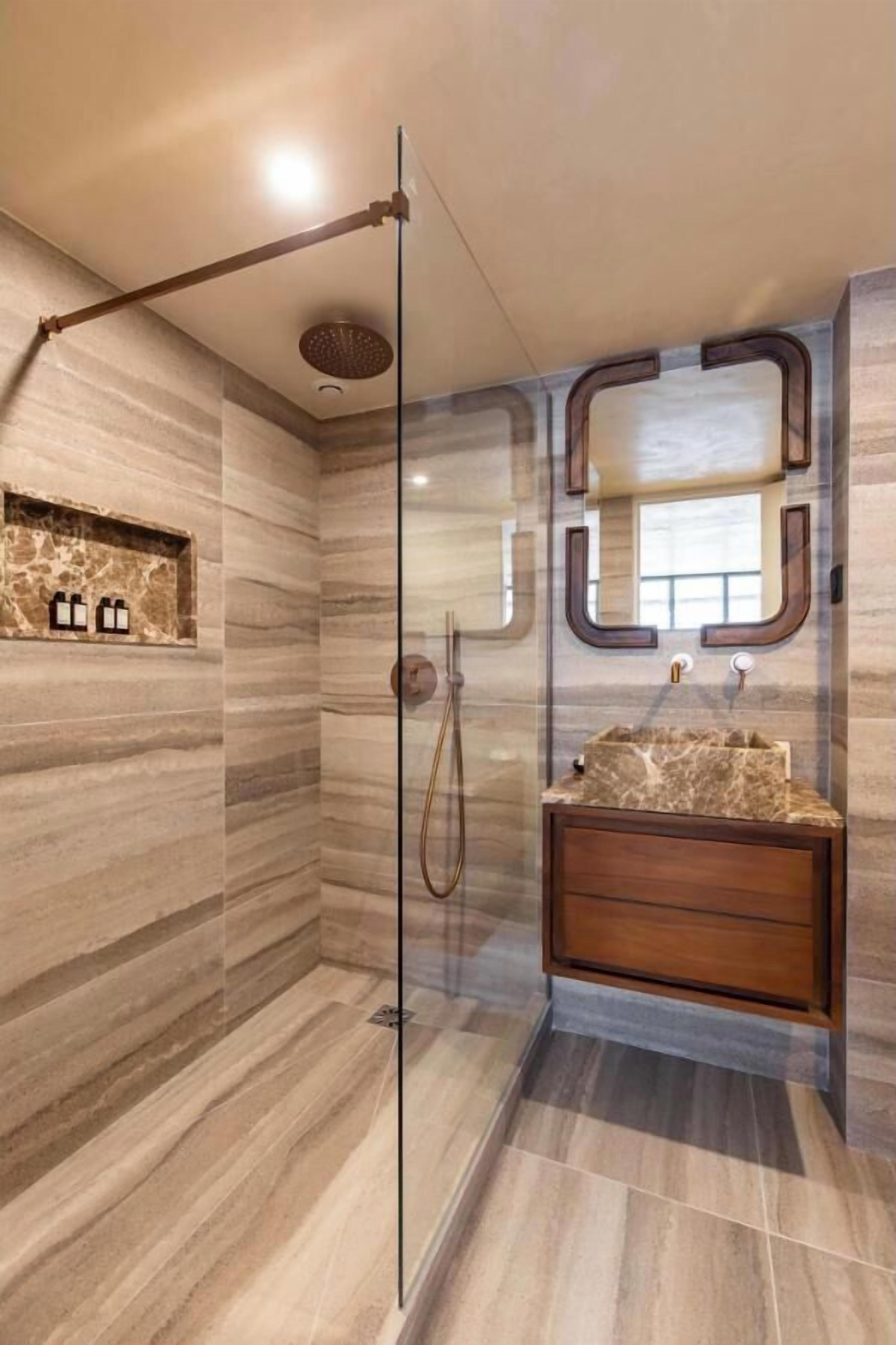 Ein modernes Badezimmer mit einer begehbaren Glasdusche, einem мраморной Waschbecken und einem Holzlagerraum.
