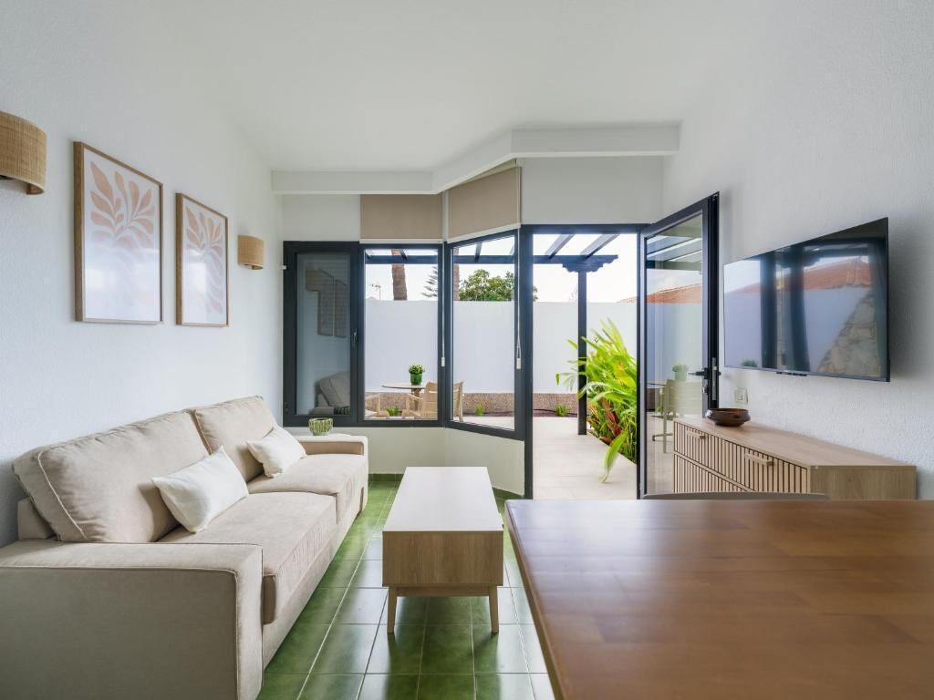 A modern living room with a sofa, coffee table, and a TV mounted on the wall.