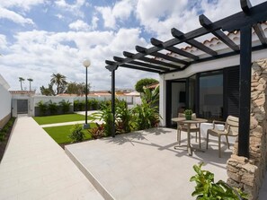 A modern outdoor patio with a pergola, a seating area with two chairs, and a well-maintained lawn. - PASO CHICO GRAN CANARIA (San Bartolomé de Tirajana)