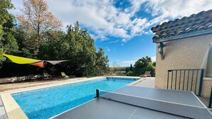 Une piscine dotée d’un parasol, de chaises longues et d’un court de tennis.