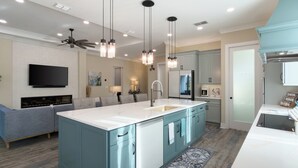Una cocina moderna con una isla central, electrodomésticos integrados e iluminación colgante.