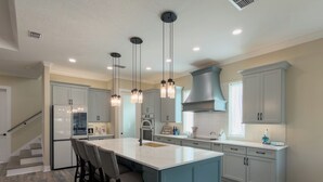 Cocina moderna con una isla central, armarios grises e iluminación colgante.