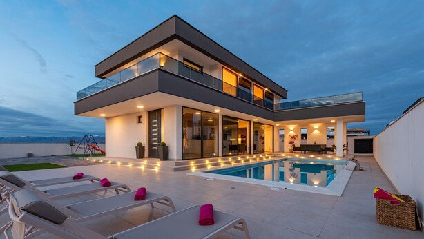 Ein modernes, zweistöckiges Haus mit Swimmingpool, Außenbereich und Bergblick.