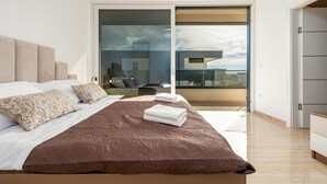 Ein modernes Schlafzimmer mit einem großen Bett, Blick auf die Stadt durch eine Schiebeglastür und einem minimalistischen Design.