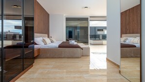 Une chambre moderne avec un mur en verre, un lit, un canapé et une petite table sur laquelle sont posées des serviettes.