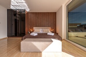Un dormitorio moderno con una cama grande, un panel de madera en la pared y vistas a través de un amplio ventanal.
