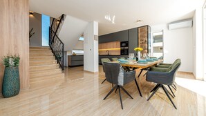 Une cuisine moderne avec un coin repas, un escalier et une grande fenêtre.