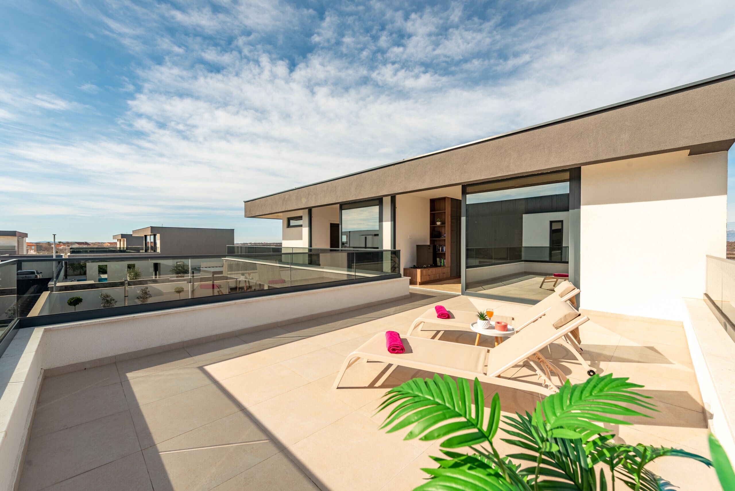 A rooftop terrace with lounge chairs, a small table, and a potted plant.