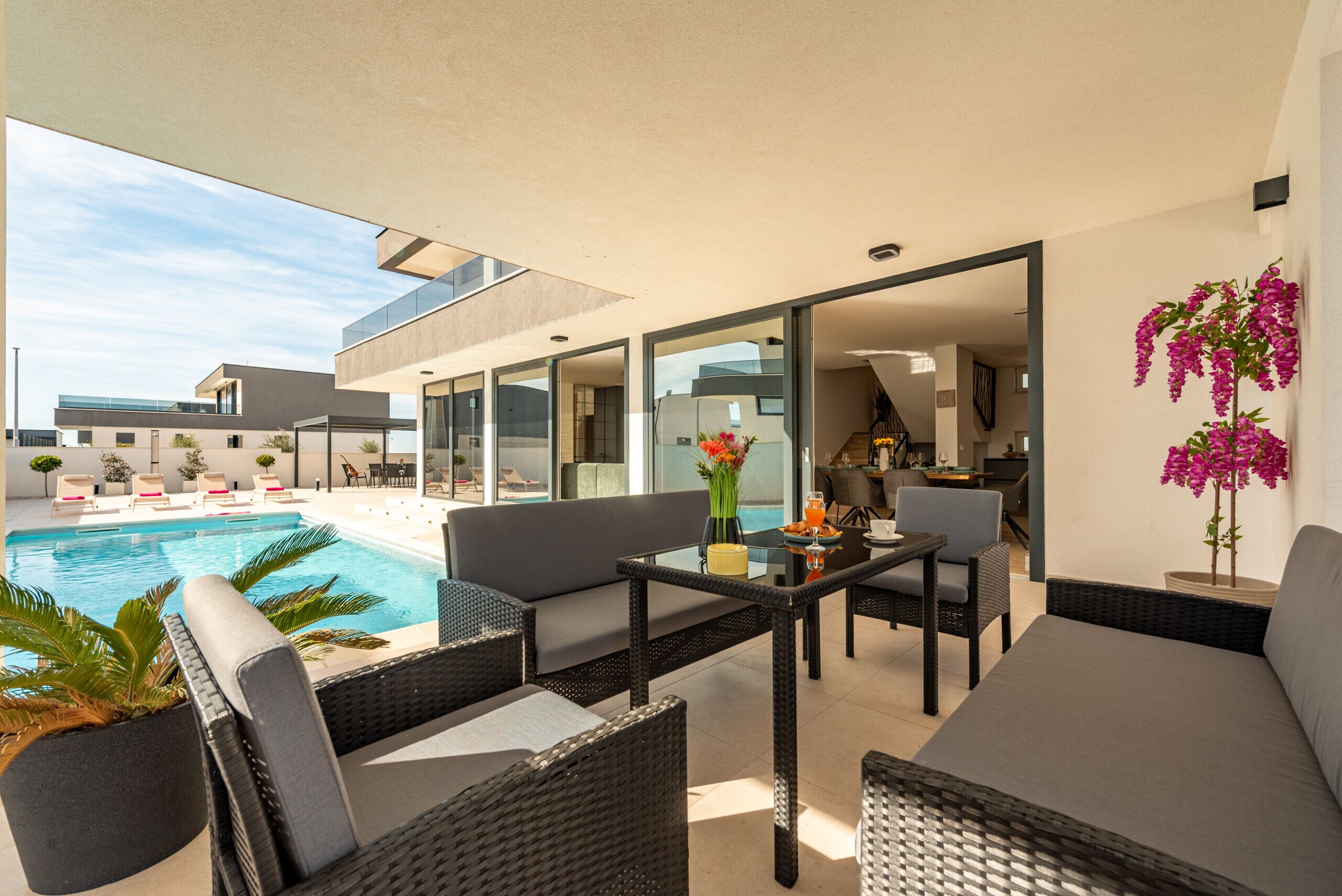 A modern outdoor lounge area with a pool, seating, and a view of the adjacent building.