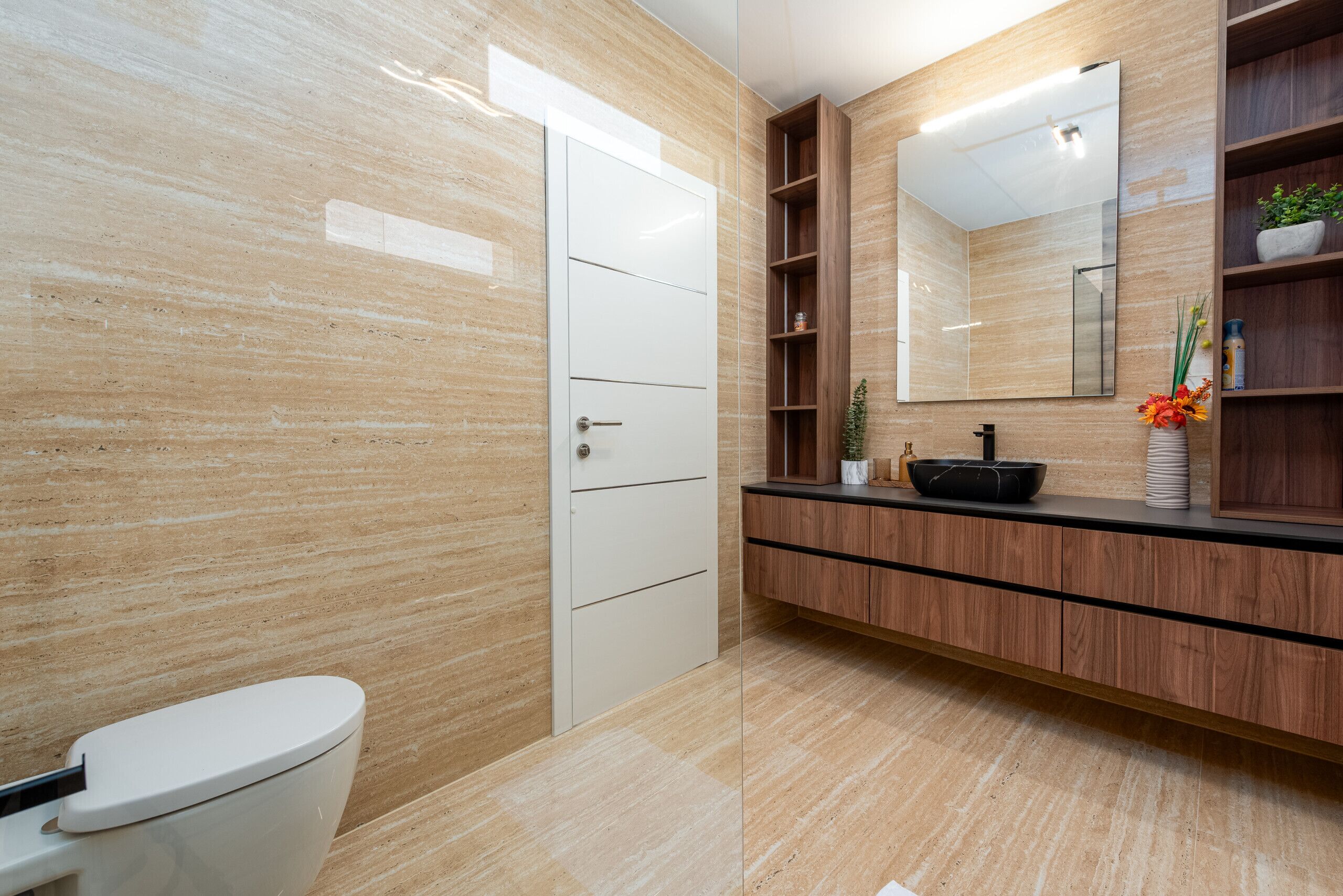 Un baño moderno con inodoro, tocador y un espejo grande.