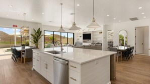 Una cocina amplia con una isla central, iluminación colgante y vistas al exterior.