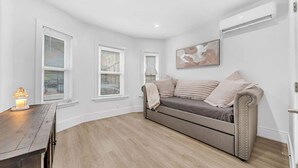 Ein modernes Wohnzimmer mit grauem Sofa, weißen Wänden und Holzboden.
