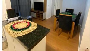 Ein kompakter Wohnraum mit Küchenzeile, Essbereich und kleinem Fernseher.
