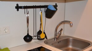 Une cuisine équipée d’un évier en acier inoxydable, d’une cuisinière noire et d’un porte-ustensiles contenant divers accessoires de cuisine.