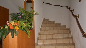 Un escalier recouvert de carreaux beiges, une main courante en bois et un miroir fixé au mur.